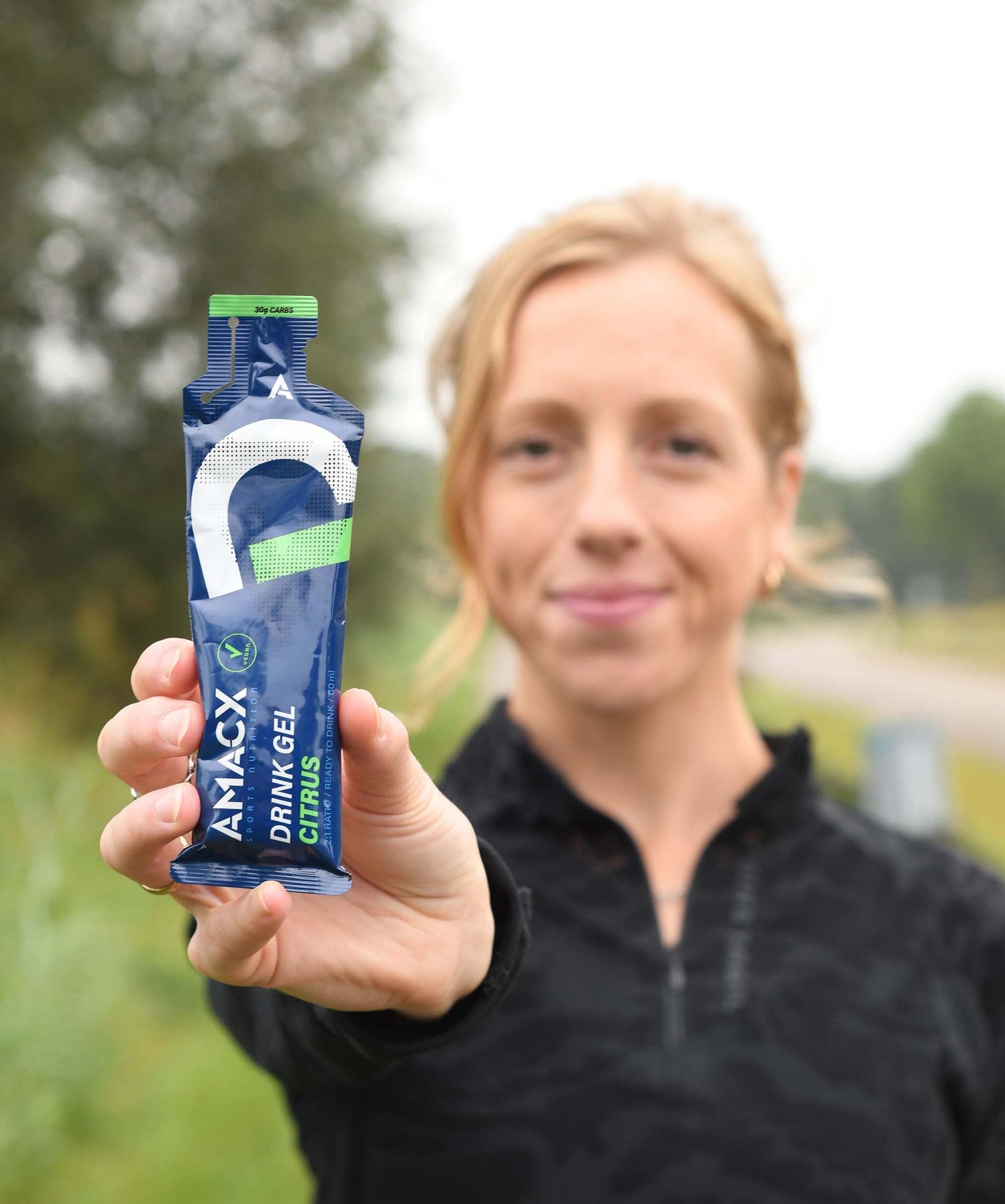 Woman holding Drink Gel Citrus | 12-pack pouch in focus outdoors, gallery position 2, portrait orientation 2048x2454 pixels