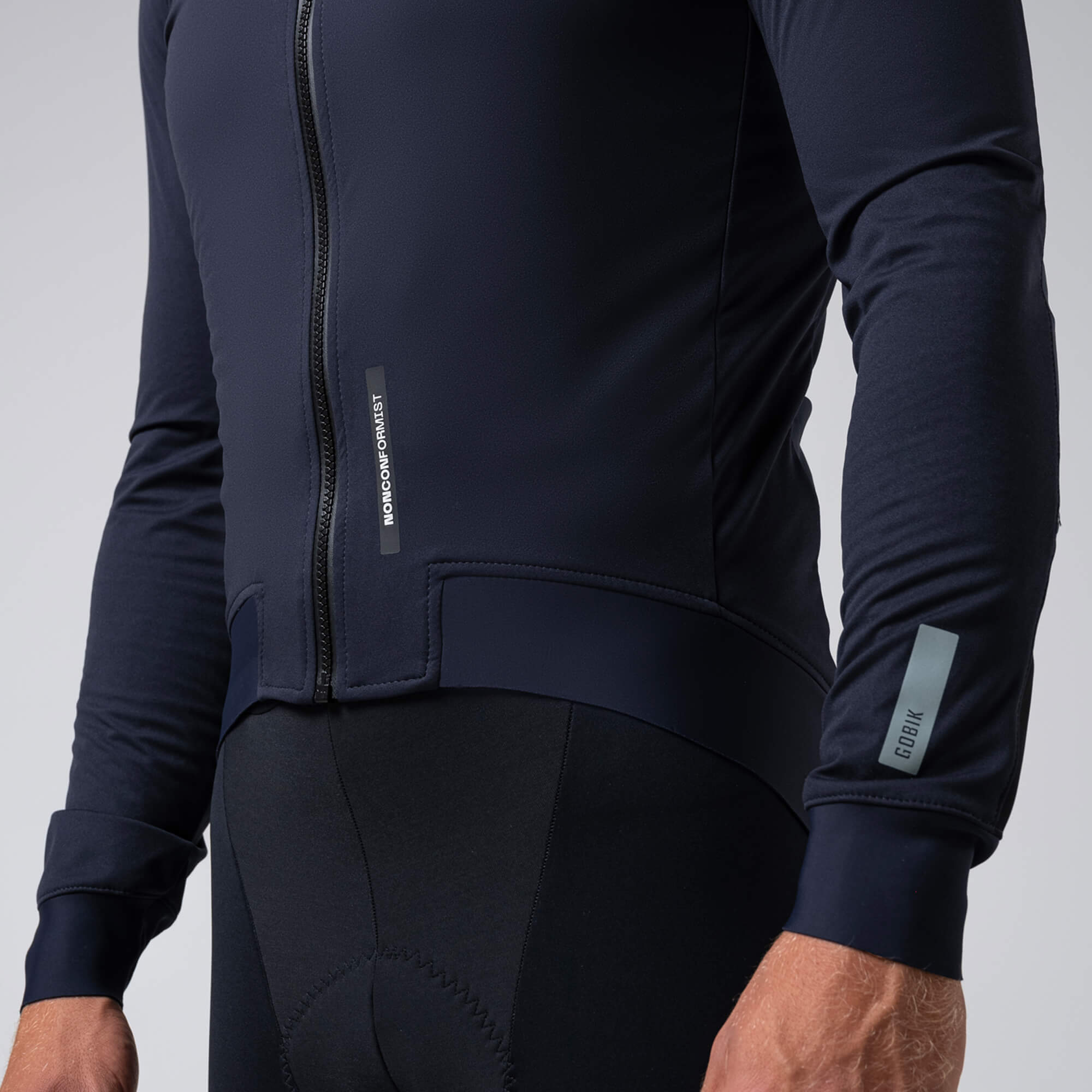 Close-up of a person wearing GOBIK Armour 2.0 Thermal Jacket - Unisex showing zipper and reflective logo on sleeve