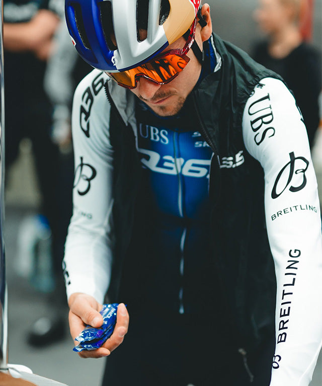 Cyclist in racing gear holding a pack of Amacx Energy Fruit Chew Cassis before a race.