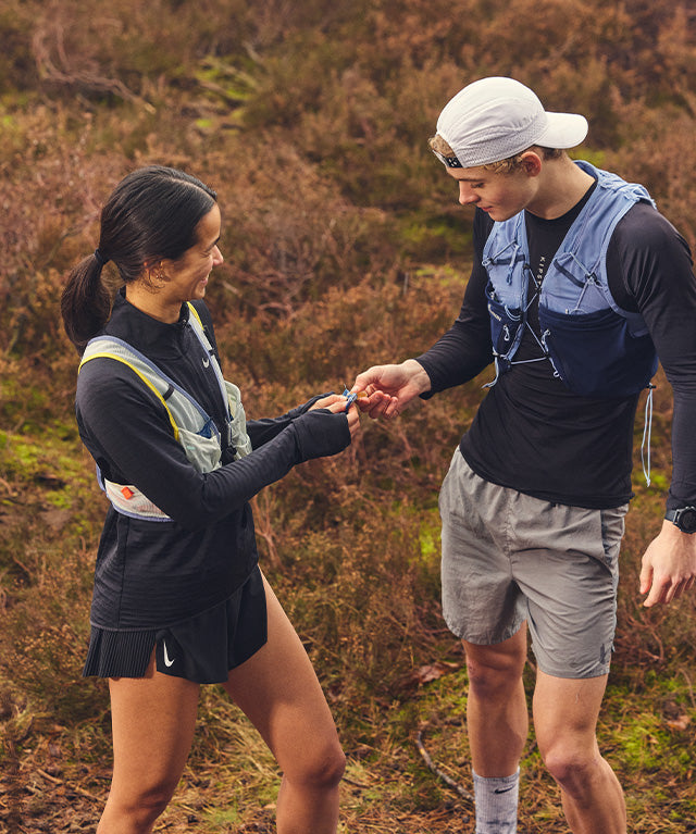 Energy Fruit Chew Piña 12 pack shown in outdoor setting with two hikers sharing energy during a trail run portrait gallery 2