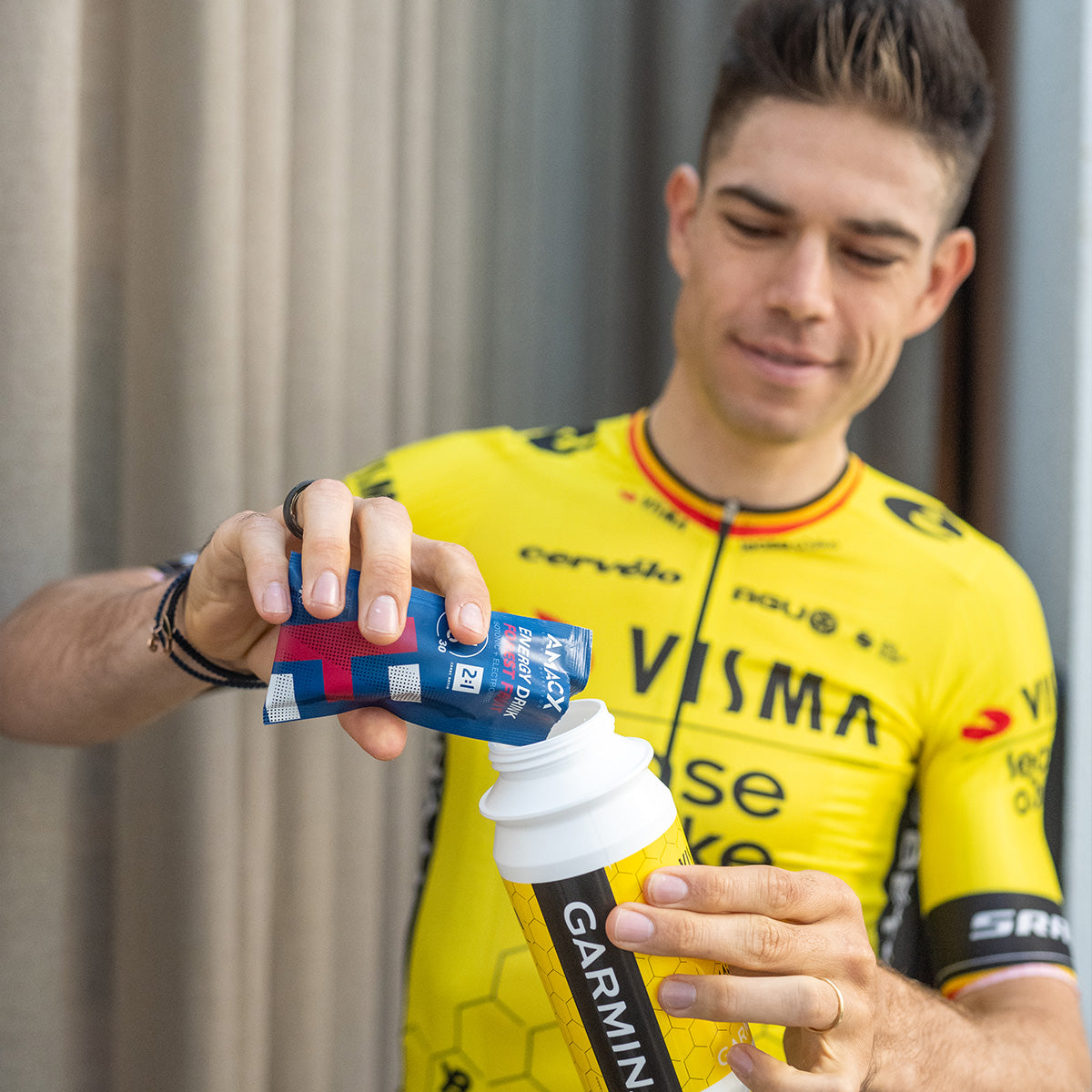 Man in yellow cycling jersey pouring Amacx Energy Drink On The Go into a Garmin water bottle outdoors