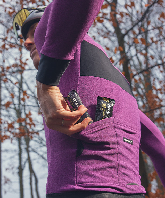 Athlete placing Turbo Fruit Chew Cassis | 12 Pack energy chews into a jersey back pocket outdoors portrait view
