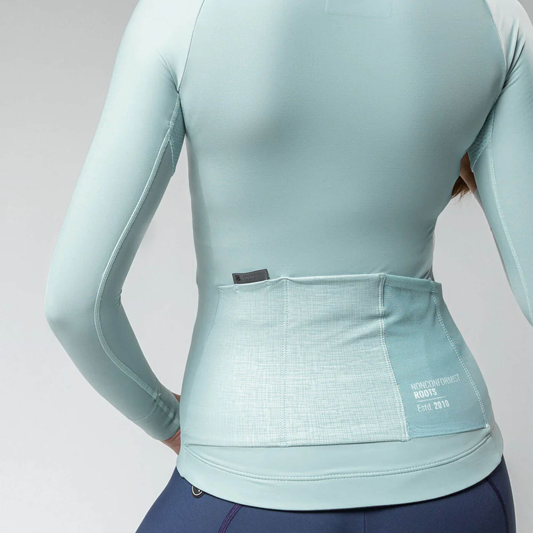 Back view of a woman wearing GOBIK Pacer Solid Long Sleeve Jersey - Women's with rear pockets in light blue fabric