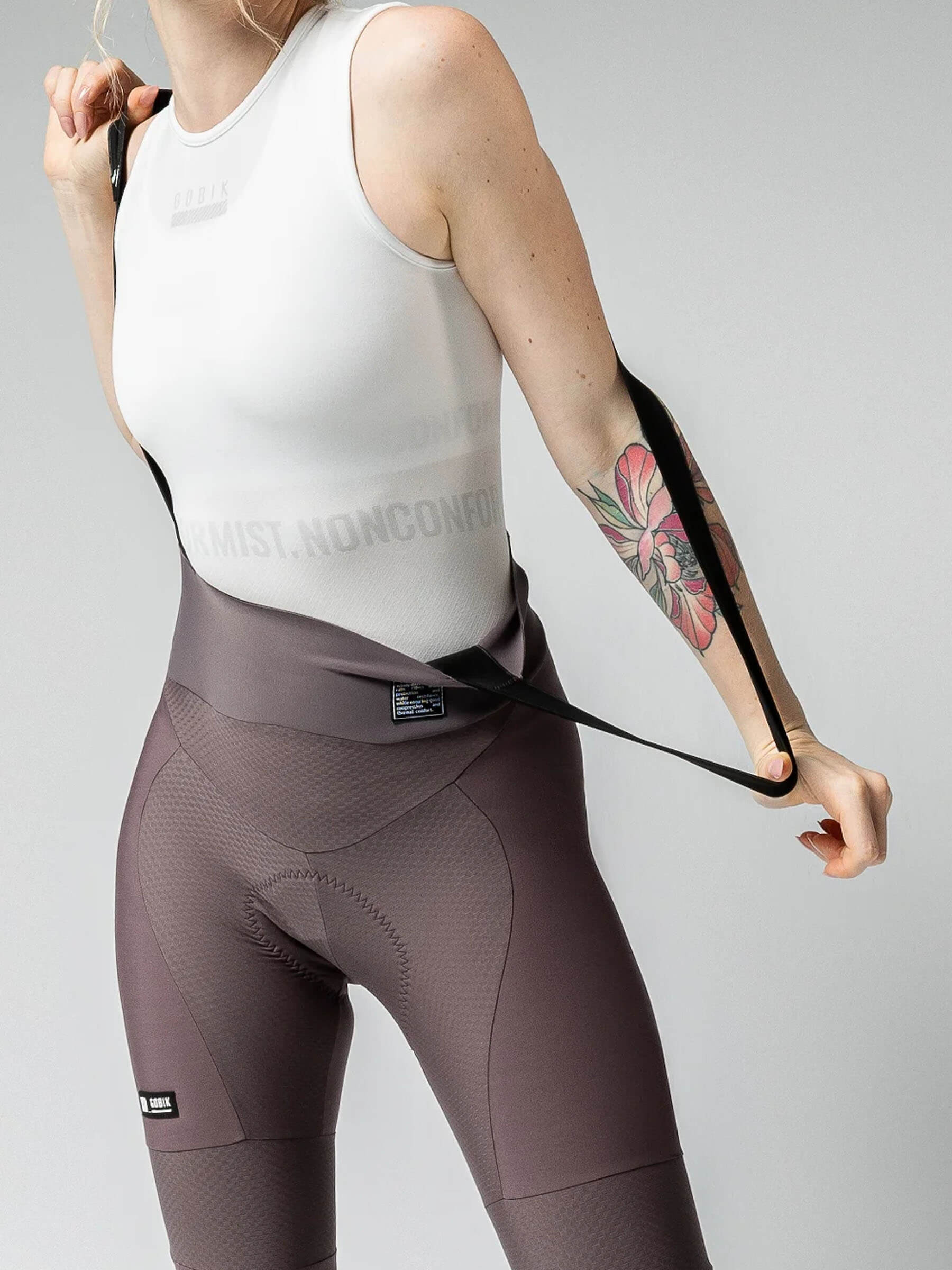 Woman adjusting straps wearing GOBIK Absolute 6.0 K9 Bib Tights - Women's in muted purple with ergonomic stitching