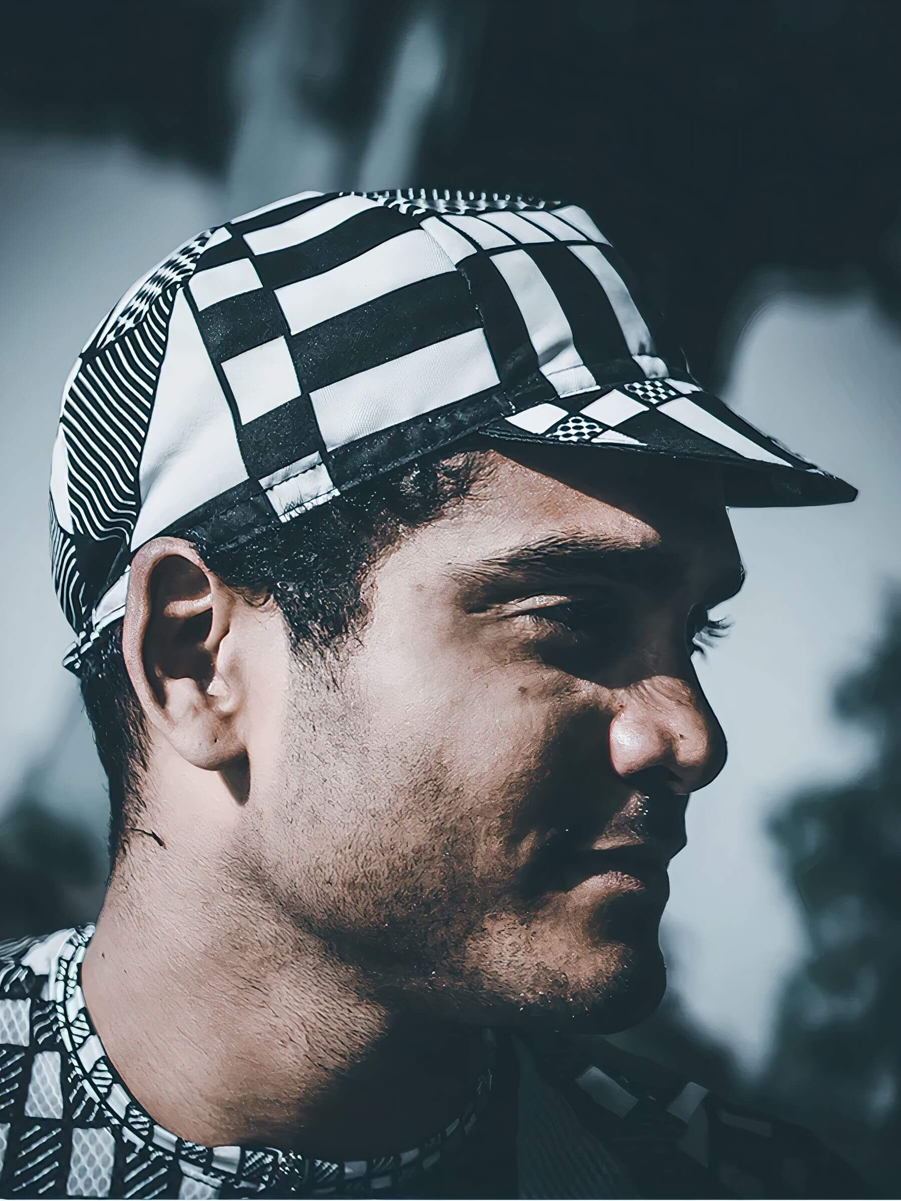 Man wearing Ostroy Letraset Cap in black and white geometric pattern with short brim against blurred background