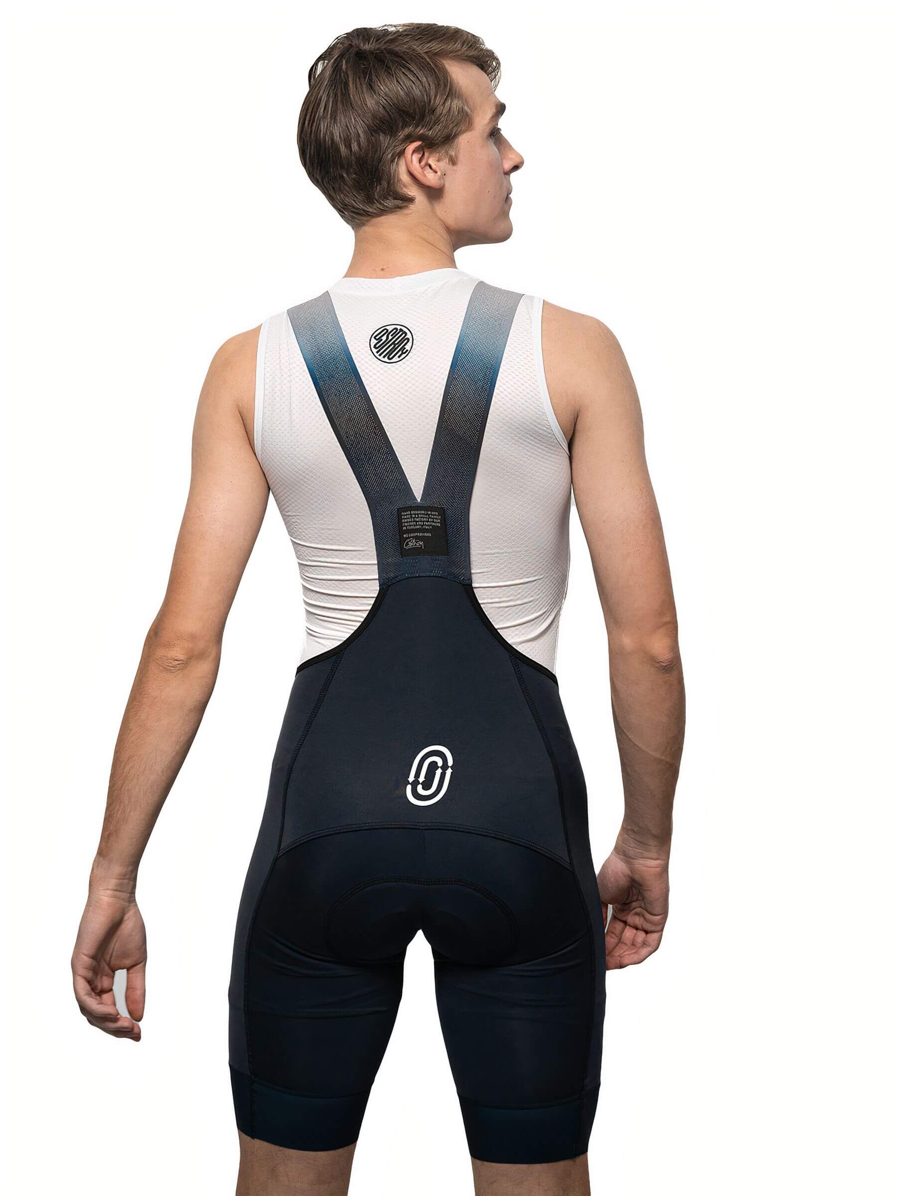 Back view of man wearing Ostroy NoMad Bibs - Men's with clean, functional design and supportive mesh straps against white background