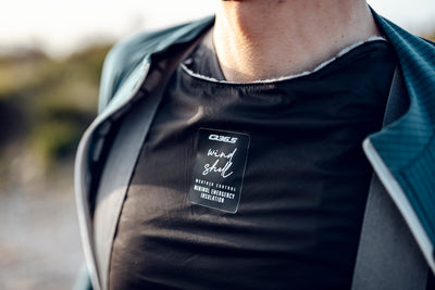 Close-up of the Q36.5 Wind Shell worn by a cyclist, focusing on the emergency insulation's fit and functionality.