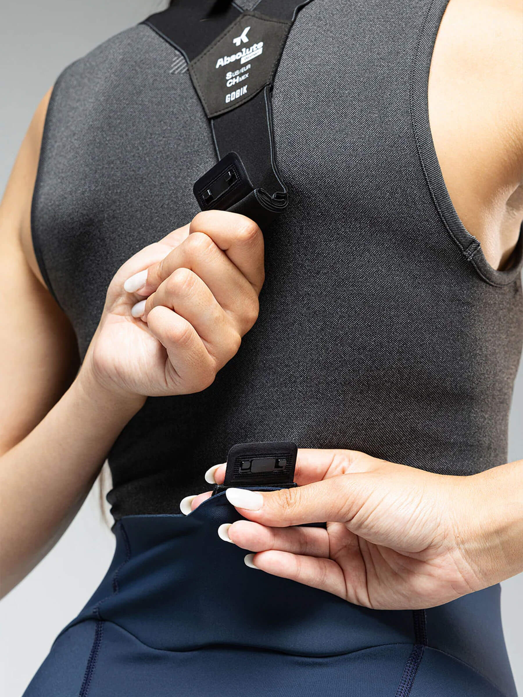 Close-up of a woman securing the straps on the GOBIK Absolute 6.0 K9 Bib Tights - Women's in navy blue
