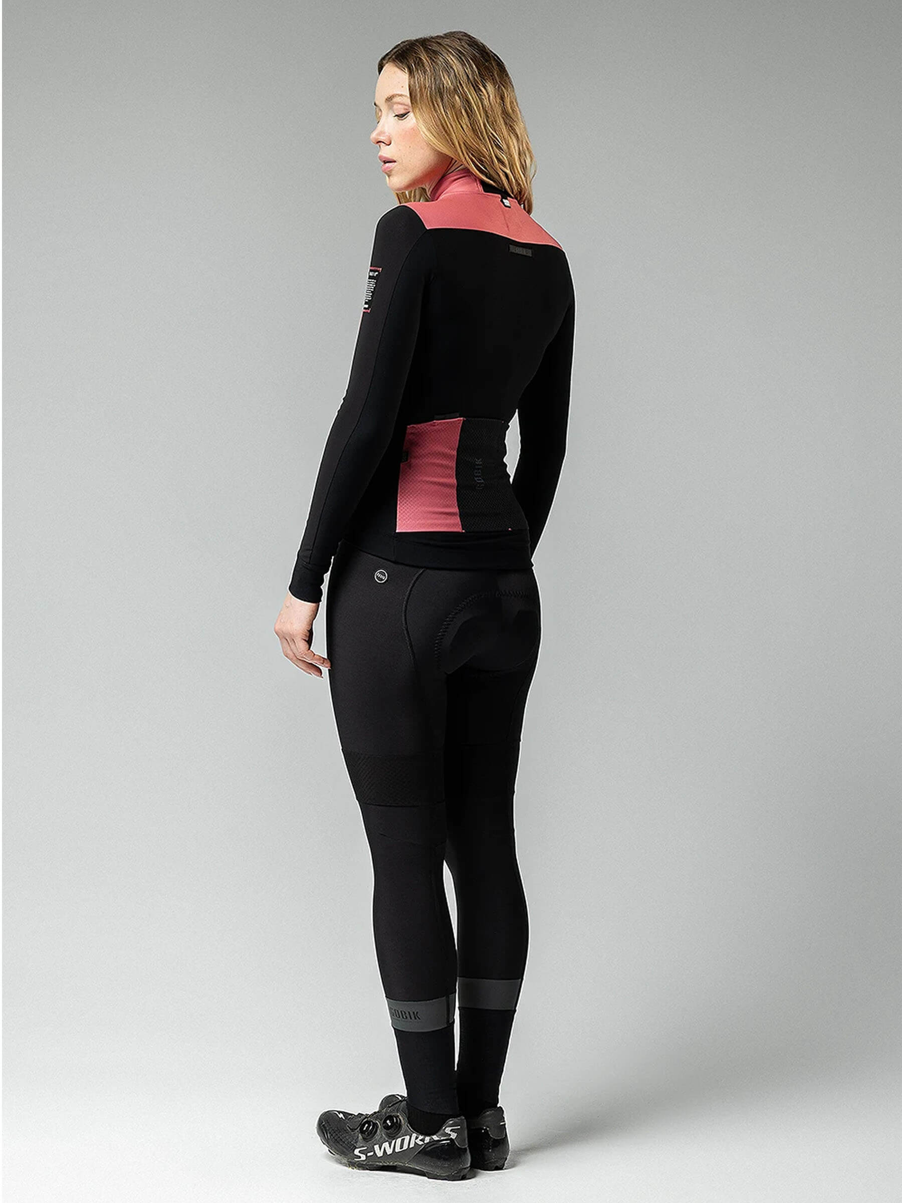 Woman wearing GOBIK Mist Blend 2.0 Jacket - Women's with color block design and high collar standing against grey background
